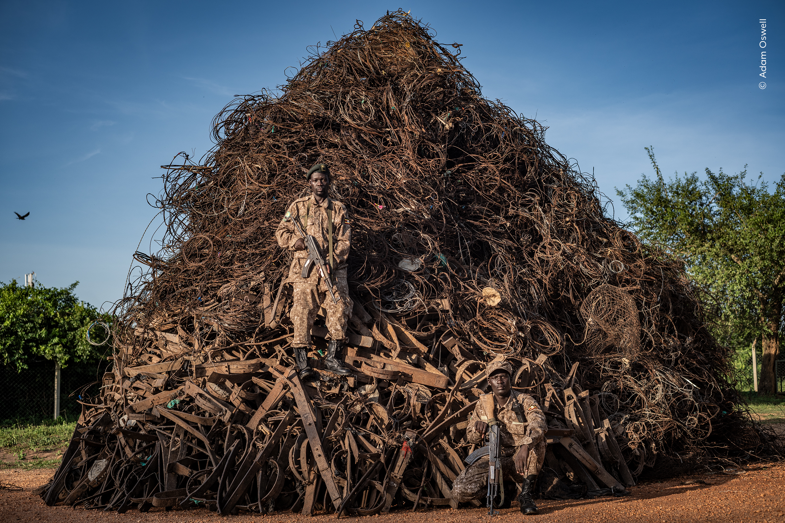 "Portrait of Extinction" depicts mountainous pile of confiscated snares lies behind Uganda Wildlife Authority rangers.